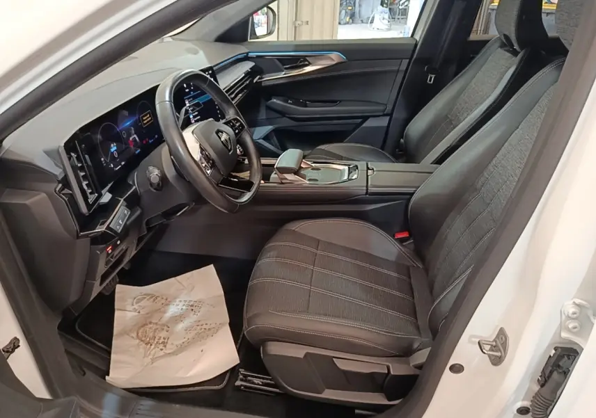 Vue intérieure côté conducteur du Renault Austral blanc 2023, avec tableau de bord digital et sièges tissu noir.