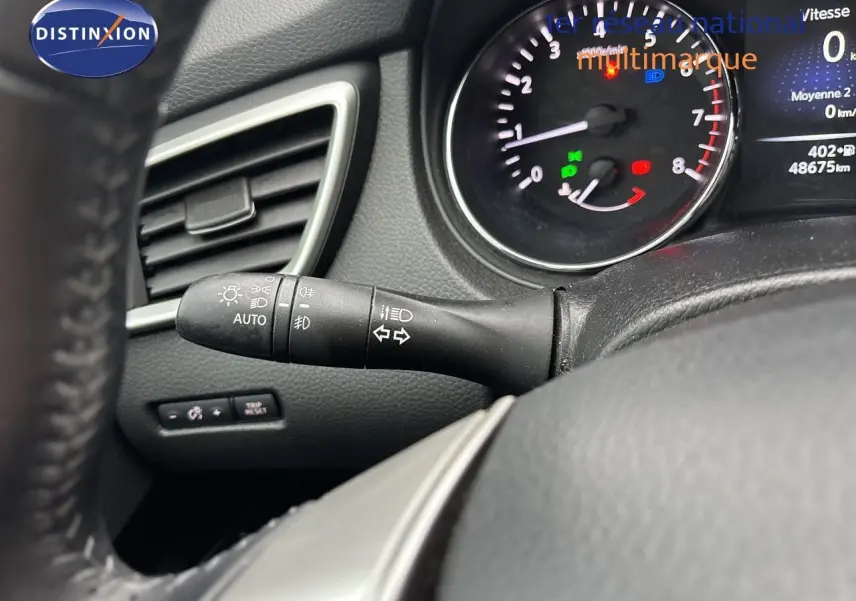 Gros plan sur le commodo des phares et clignotants à gauche du volant, tableau de bord noir du Nissan Qashqai 2017.