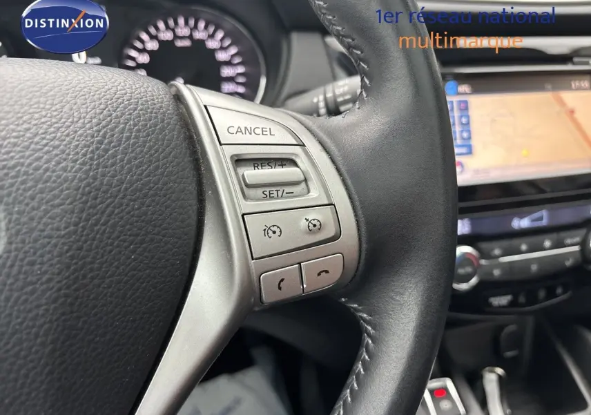 Gros plan sur le volant noir du Nissan Qashqai blanc glacier, avec commandes de régulateur de vitesse visibles.