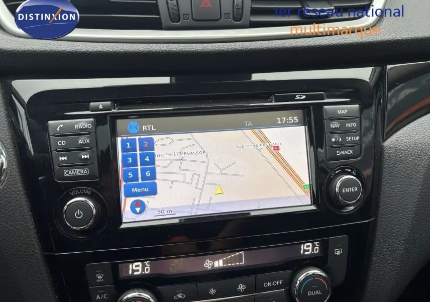 Vue rapprochée de la console centrale du Nissan Qashqai blanc glacier, mettant en valeur l'écran tactile GPS et les commandes de climatisation.
