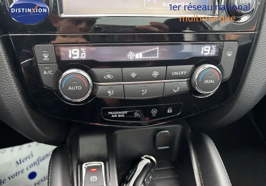 Tableau de bord du Nissan Qashqai 2017 en gros plan, montrant la climatisation automatique et les commandes centrales.