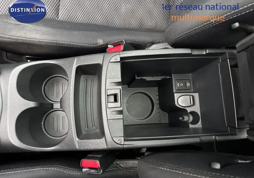Vue plongeante sur la console centrale noire du Nissan Qashqai 2017, avec porte-gobelets et compartiment ouvert.
