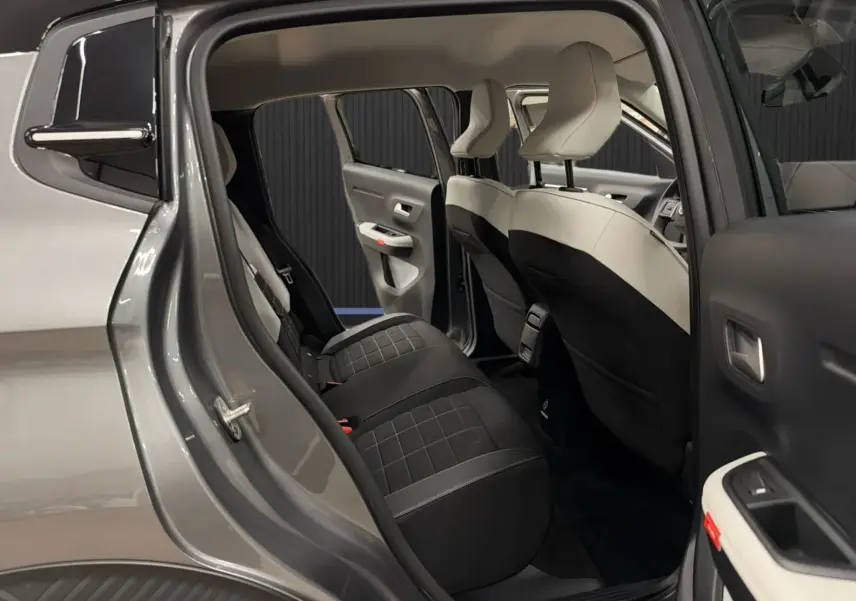 Vue intérieure côté gauche arrière de la Citroën E-C3 2025 gris, montrant les sièges bicolores et l'ouverture des portières.