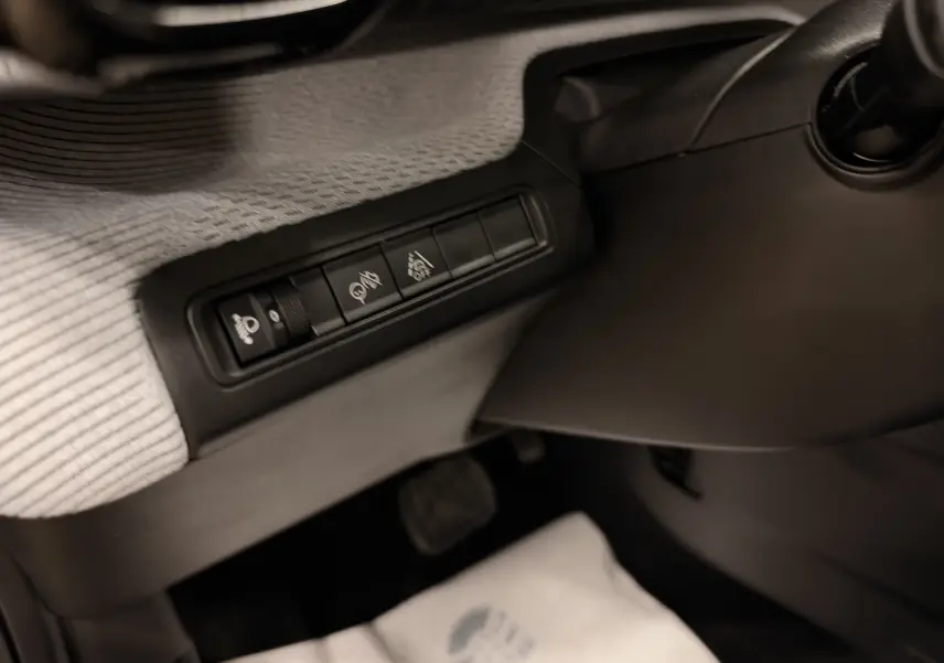 Détail des commandes situées à gauche du volant dans l’habitacle noir du Citroën E-C3 gris 2025.