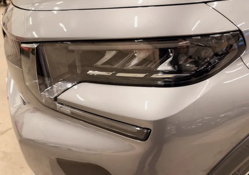 Gros plan sur le phare avant droit gris métallisé du Citroën E-C3 2025, mettant en valeur son design moderne et épuré.