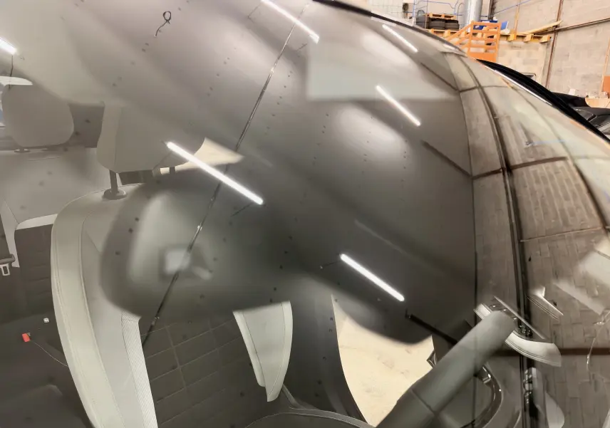Vue intérieure côté conducteur d'une Citroën C3 électrique gris 2025, montrant les sièges et le volant partiellement visibles.