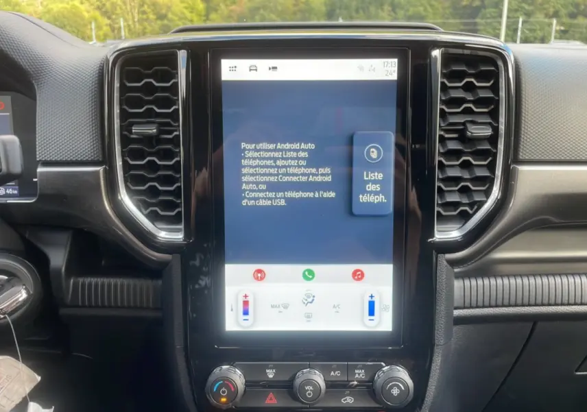 Vue rapprochée du tableau de bord noir du Ford Ranger 2025, mettant en valeur l'écran tactile central et les commandes climatisation.