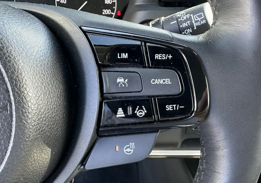 Gros plan sur les commandes du volant cuir noir du Honda HR-V 2025, avec régulateur de vitesse et volant chauffant.