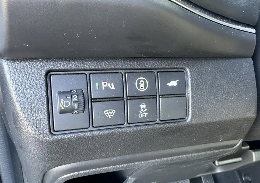 Gros plan sur les commandes de fonctions électroniques côté gauche du tableau de bord noir du Honda HR-V gris 2025.