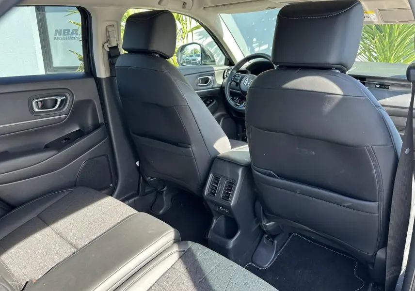 Vue intérieure arrière du Honda HR-V 2025 avec sièges noirs en cuir synthétique et tissu, et prises USB arrière visibles.