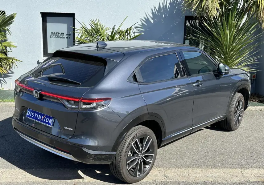 Honda HR-V gris métallisé vu en 3/4 arrière côté droit, avec feux arrière LED et jantes alliage 18 pouces.