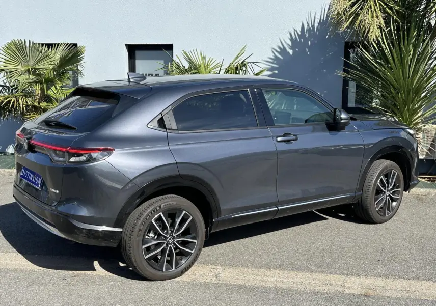 Vue 3/4 arrière droite d'un Honda HR-V gris métallisé 2025 avec jantes alliage et feux arrière LED connectés.