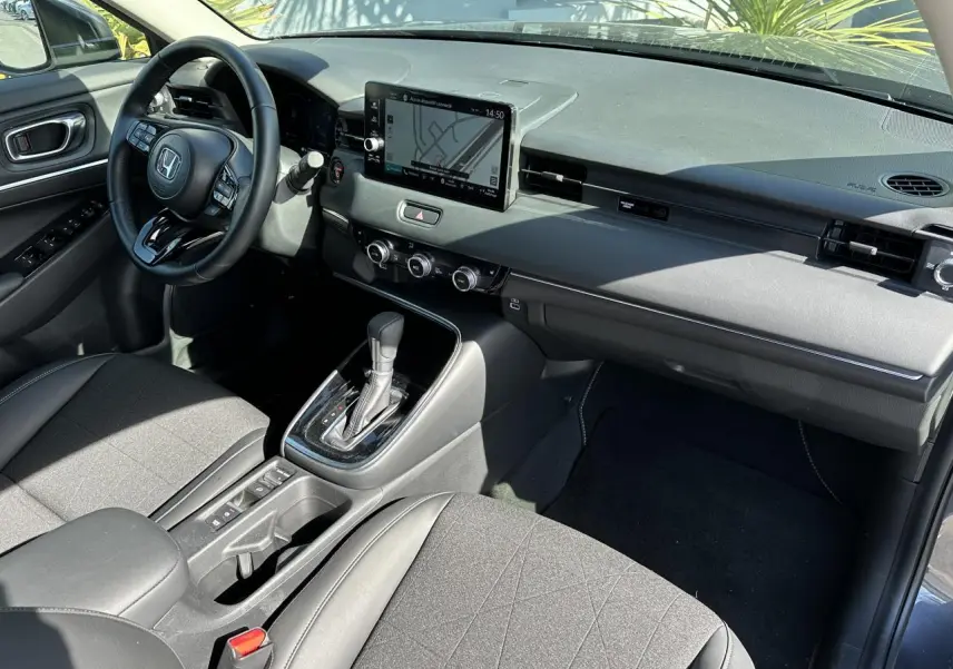 Intérieur avant droit du Honda HR-V gris 2025 avec tableau de bord moderne, écran tactile et sièges en cuir synthétique.