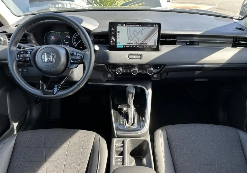 Intérieur du Honda HR-V 2025 en vue frontale, montrant le volant cuir, écran tactile et console centrale noire.