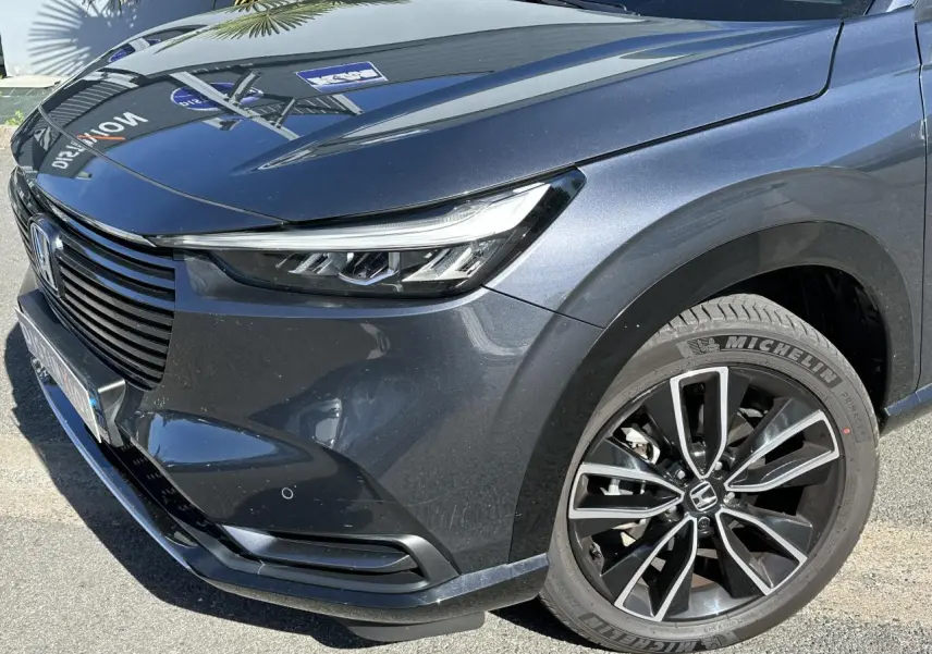 Vue 3/4 avant droit du Honda HR-V gris métallisé mettant en valeur son phare LED et jante alliage 18 pouces.