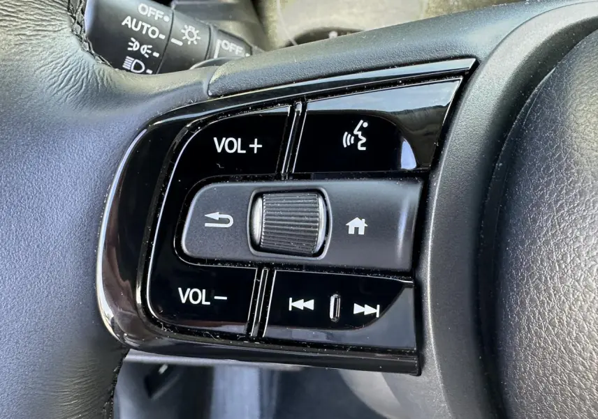 Gros plan sur les commandes audio au volant cuir noir du Honda HR-V 2025 gris hybride essence.