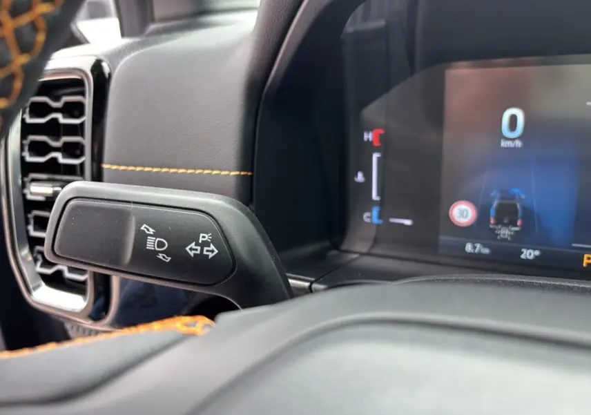 Détail du commodo de clignotant et tableau de bord numérique du Ford Ranger 2025 noir agate avec surpiqûres orange.