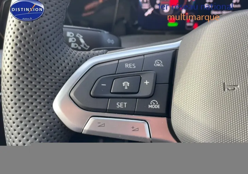 Gros plan sur les commandes du volant cuir perforé de la Volkswagen Golf gris, avec régulateur de vitesse et aides à la conduite.