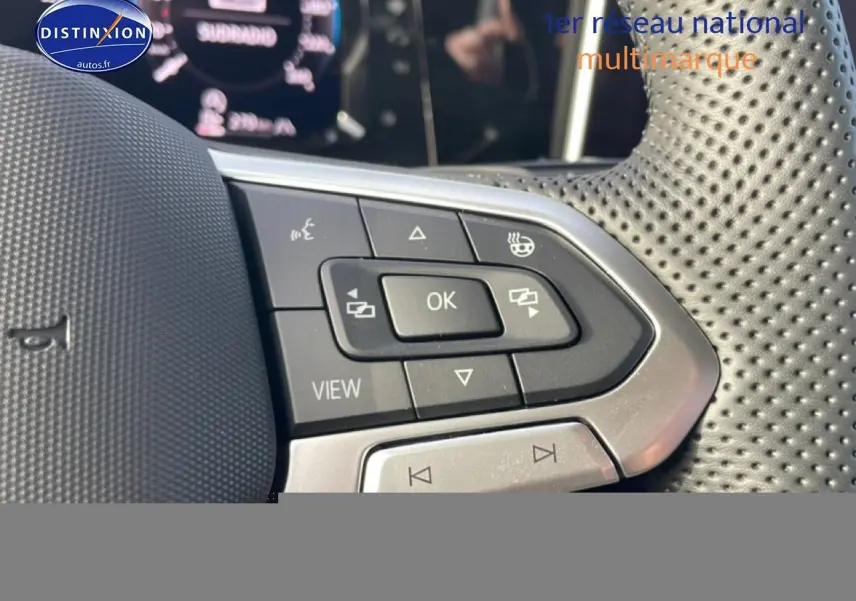 Gros plan sur les commandes multifonctions en cuir perforé du volant côté gauche d'une Volkswagen Golf gris 2026.