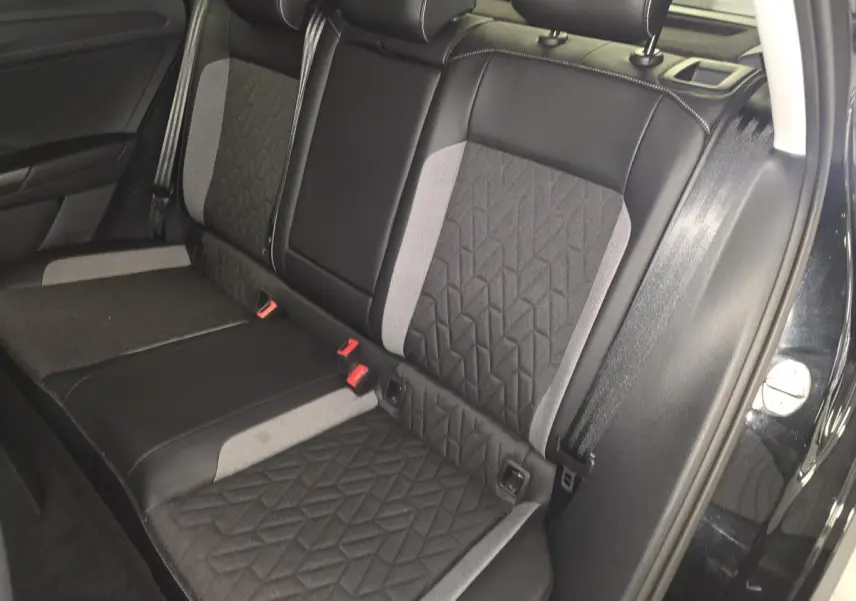 Vue latérale de la banquette arrière en tissu noir et gris du Volkswagen T-Roc noir 2025, avec ceintures de sécurité visibles.