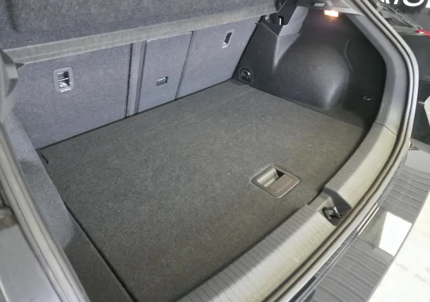 Coffre ouvert du Volkswagen T-Roc noir, vue intérieure montrant le plancher plat et les sièges arrière rabattables.