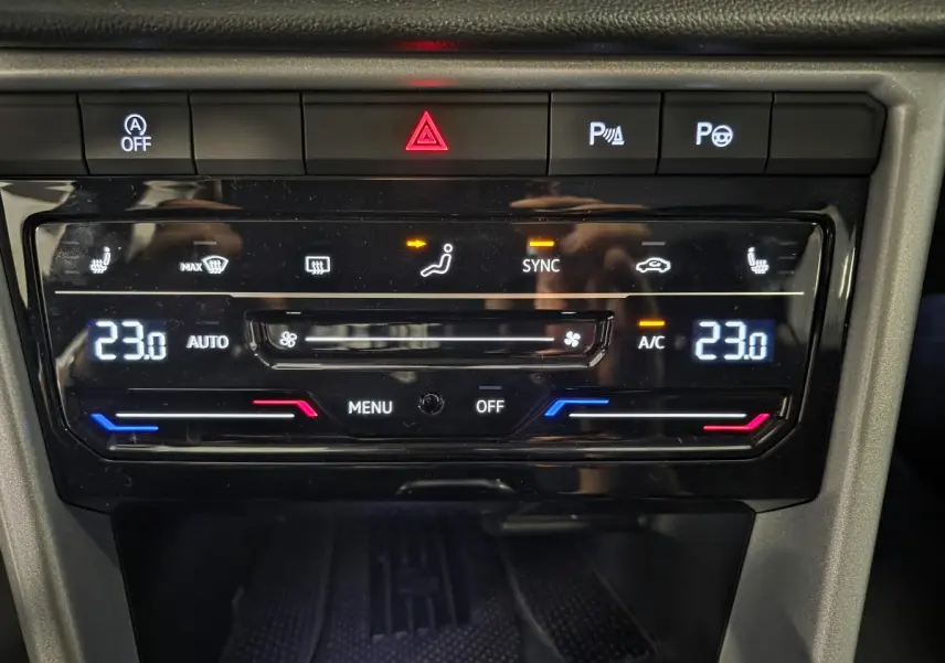 Gros plan sur la console centrale du Volkswagen T-Roc 2025 montrant la climatisation automatique bi-zone réglée à 23°C.