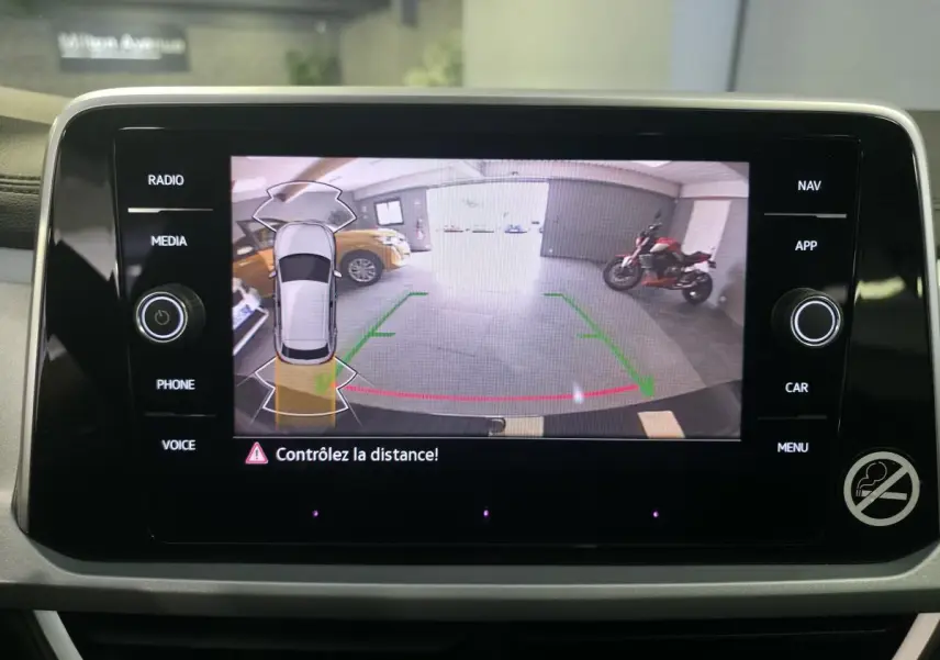 Écran tactile intérieur montrant la caméra de recul avec vue arrière et alertes de distance du Volkswagen T-Roc noir.