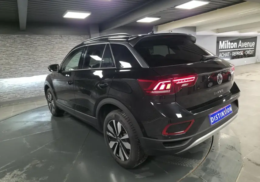 Volkswagen T-Roc noir en 3/4 arrière droit, avec feux LED allumés et jantes alliage distinctives.