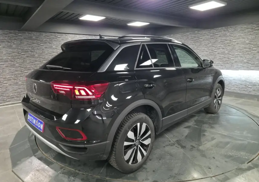 Vue 3/4 arrière droite du Volkswagen T-Roc noir nacré avec jantes alliage 17 pouces et feux arrière LED allumés.