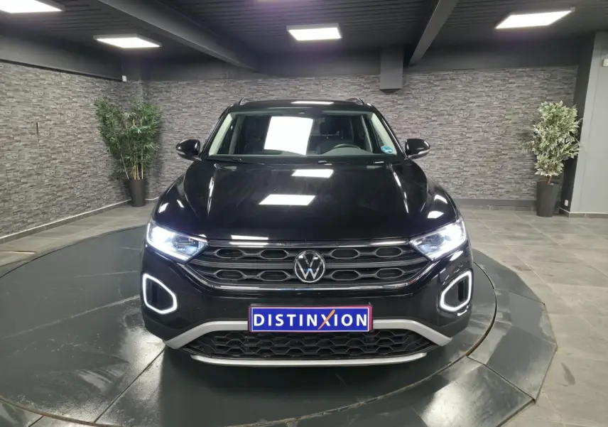 Vue frontale d'un Volkswagen T-Roc noir avec éclairage LED allumé dans un showroom intérieur.