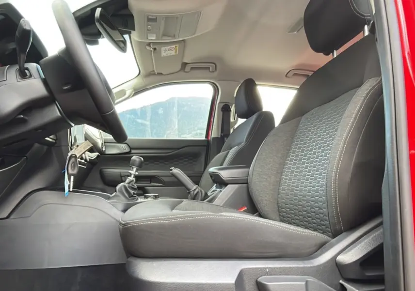 Intérieur du Ford Ranger 2025 rouge racing, vue côté conducteur montrant sièges noirs et levier de vitesses manuel.