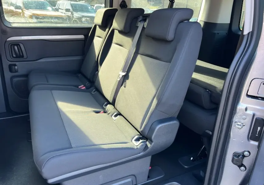 Vue intérieure côté droit sur la banquette arrière grise du Peugeot Traveller 2025 avec porte coulissante ouverte.