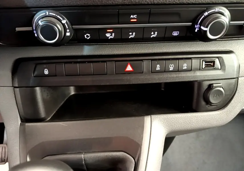 Détail du tableau de bord du Peugeot Traveller 2018, montrant les commandes de climatisation et la console centrale avec prise 12V.
