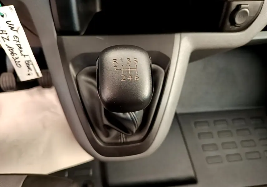 Gros plan sur le levier de vitesses manuel noir du Peugeot Traveller blanc de 2018, montrant les six rapports et la marche arrière.