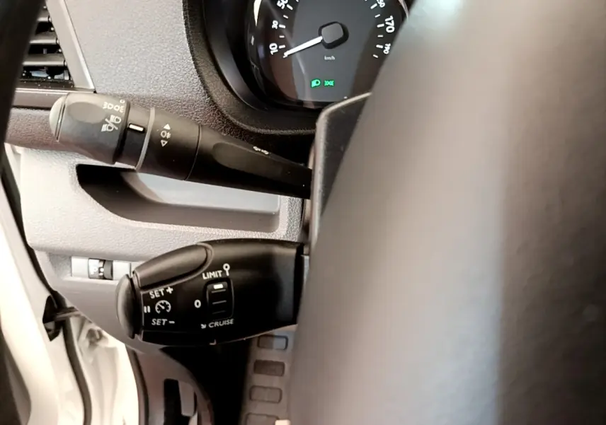 Gros plan sur la commande de régulateur de vitesse et clignotants du Peugeot Traveller blanc, vue côté gauche du volant.