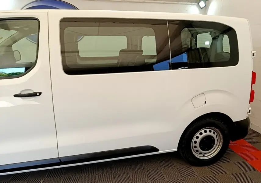 Vue de profil côté droit d’un Peugeot Traveller blanc 2018 avec vitres teintées et jantes acier.
