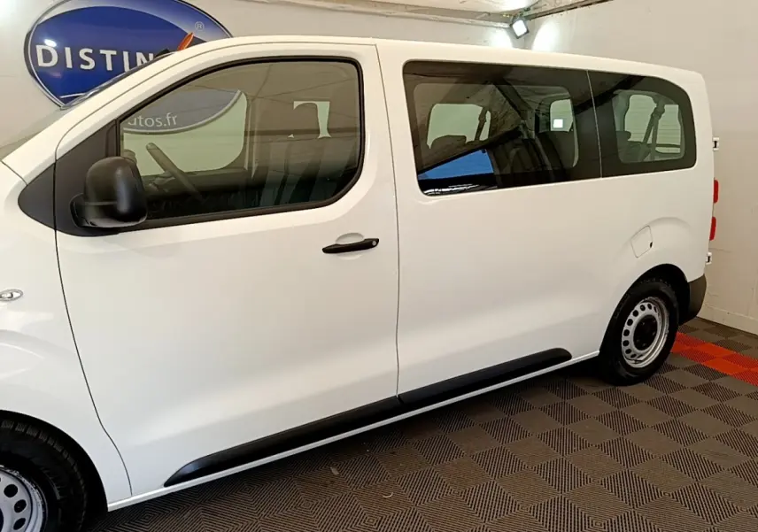 Vue de profil côté gauche d’un Peugeot Traveller blanc 2018 avec vitres teintées et jantes acier noires.