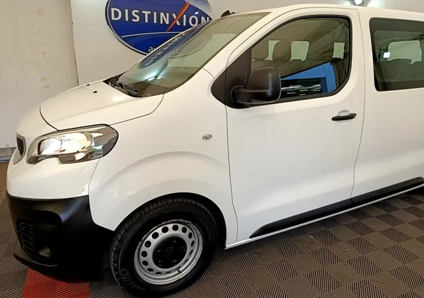 Vue de profil côté gauche d’un Peugeot Traveller blanc 2018 avec pare-chocs avant noir et jantes acier.
