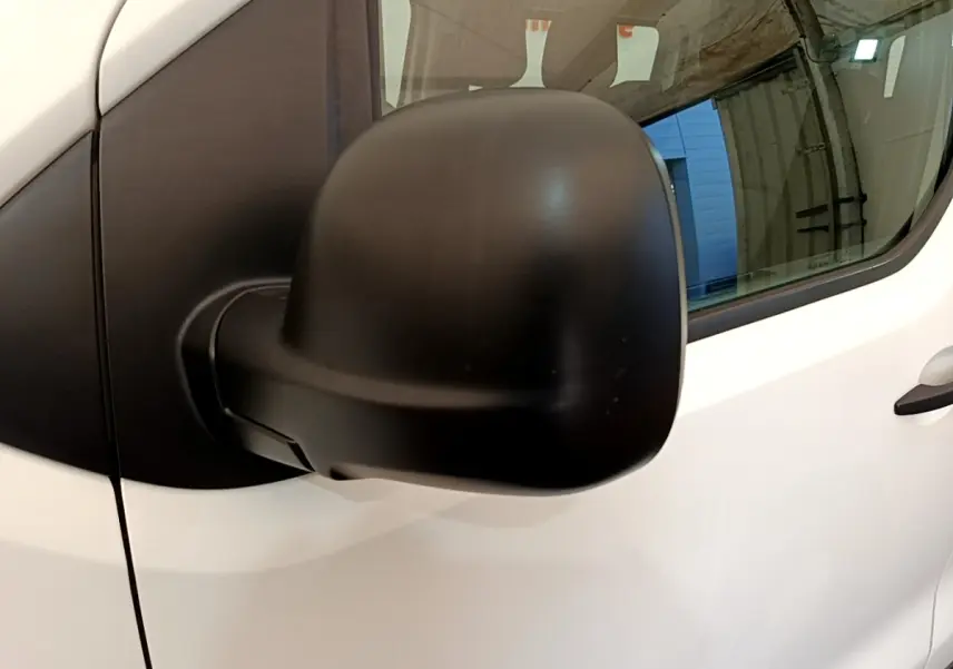 Rétroviseur noir en gros plan côté gauche d’un Peugeot Traveller blanc de 2018, avec porte et vitre visibles.
