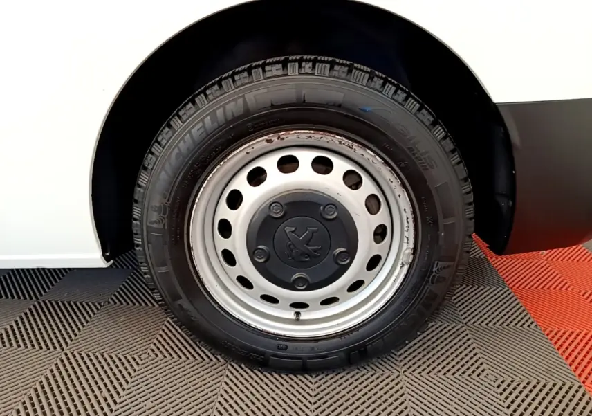 Gros plan sur la roue avant droite d’un Peugeot Traveller blanc de 2018 avec jante acier et pneu Michelin.