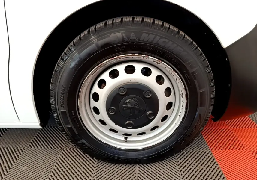 Gros plan sur la roue avant gauche blanche d’un Peugeot Traveller 2018 avec jante acier et pneu Michelin.