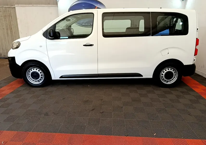 Vue de profil côté gauche d'un Peugeot Traveller blanc de 2018 avec jantes acier et vitres teintées arrière.