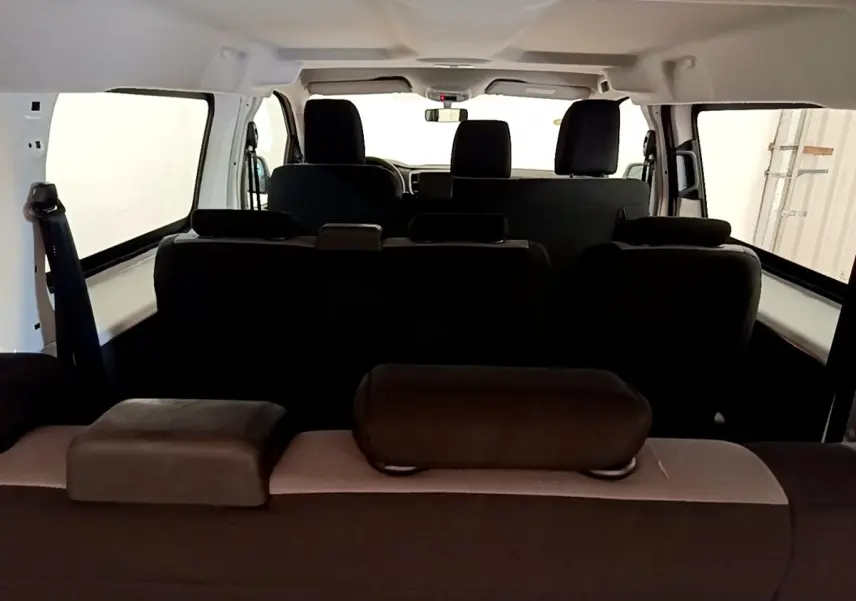 Vue intérieure arrière du Peugeot Traveller blanc 2018, montrant les sièges noirs et l'habitacle spacieux.