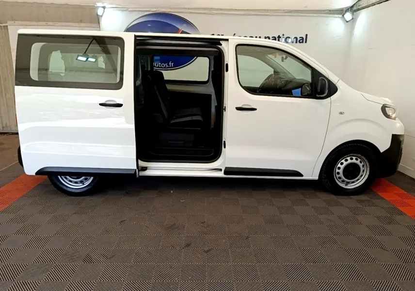 Vue latérale droite d'un Peugeot Traveller blanc 2018 avec porte coulissante ouverte, intérieur visible et jantes acier noires.