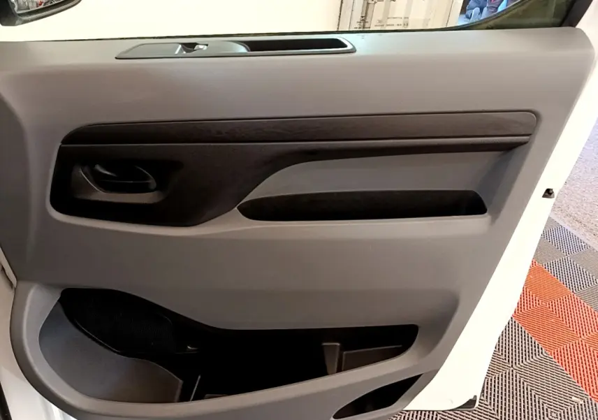 Vue rapprochée de la porte intérieure côté droit du Peugeot Traveller blanc 2018, avec poignée et rangements visibles.