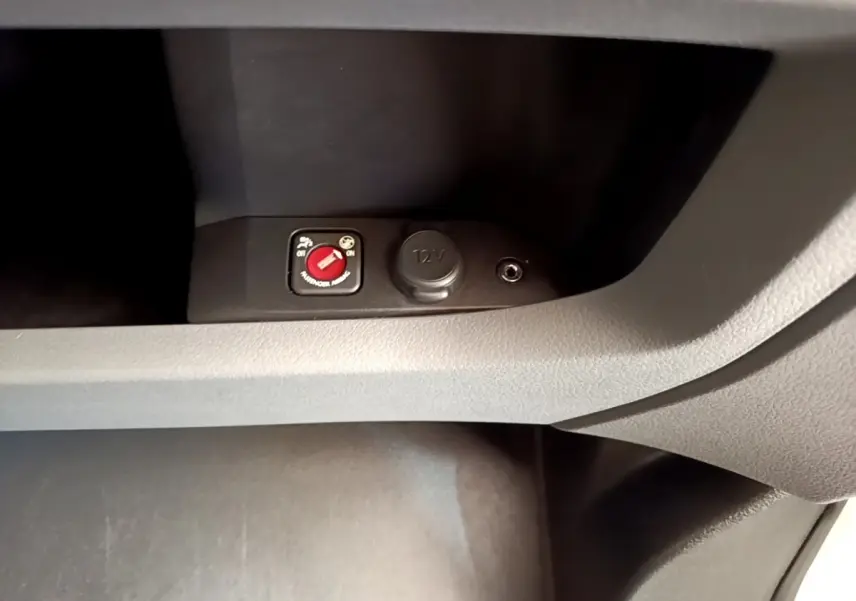Détail intérieur du Peugeot Traveller 2018 montrant un interrupteur rouge et une prise 12V dans la console centrale.