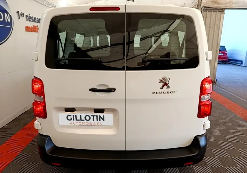 Vue arrière d’un Peugeot Traveller blanc de 2018 avec portes battantes et feux rouges allumés en intérieur.
