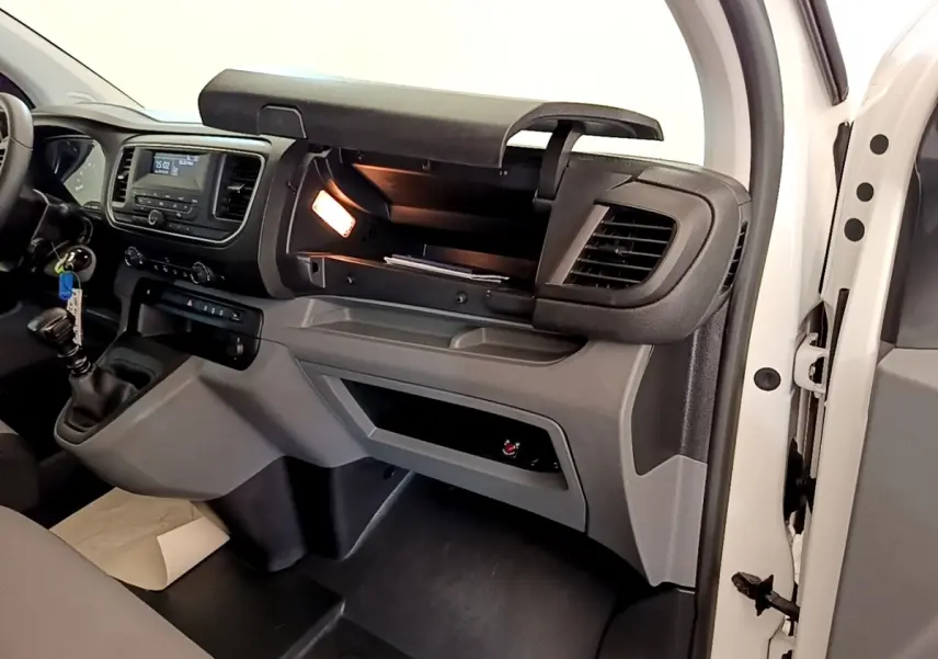 Intérieur du Peugeot Traveller blanc 2018, vue côté passager avec boîte à gants ouverte et tableau de bord visible.