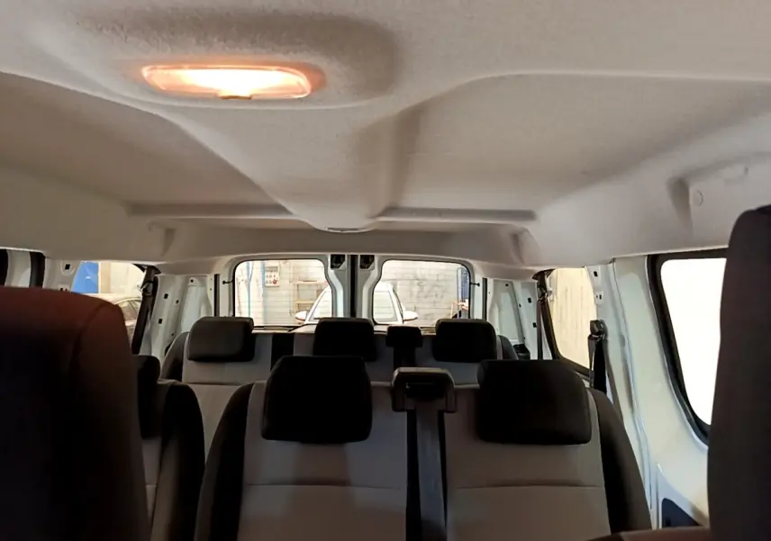 Vue intérieure arrière du Peugeot Traveller blanc 2018 montrant les sièges passagers et la lumière de plafond allumée.