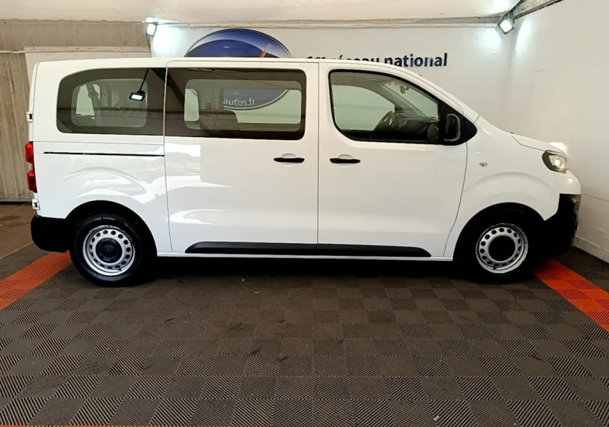 Vue de profil côté gauche d’un Peugeot Traveller blanc de 2018 avec jantes acier et vitres teintées arrière.